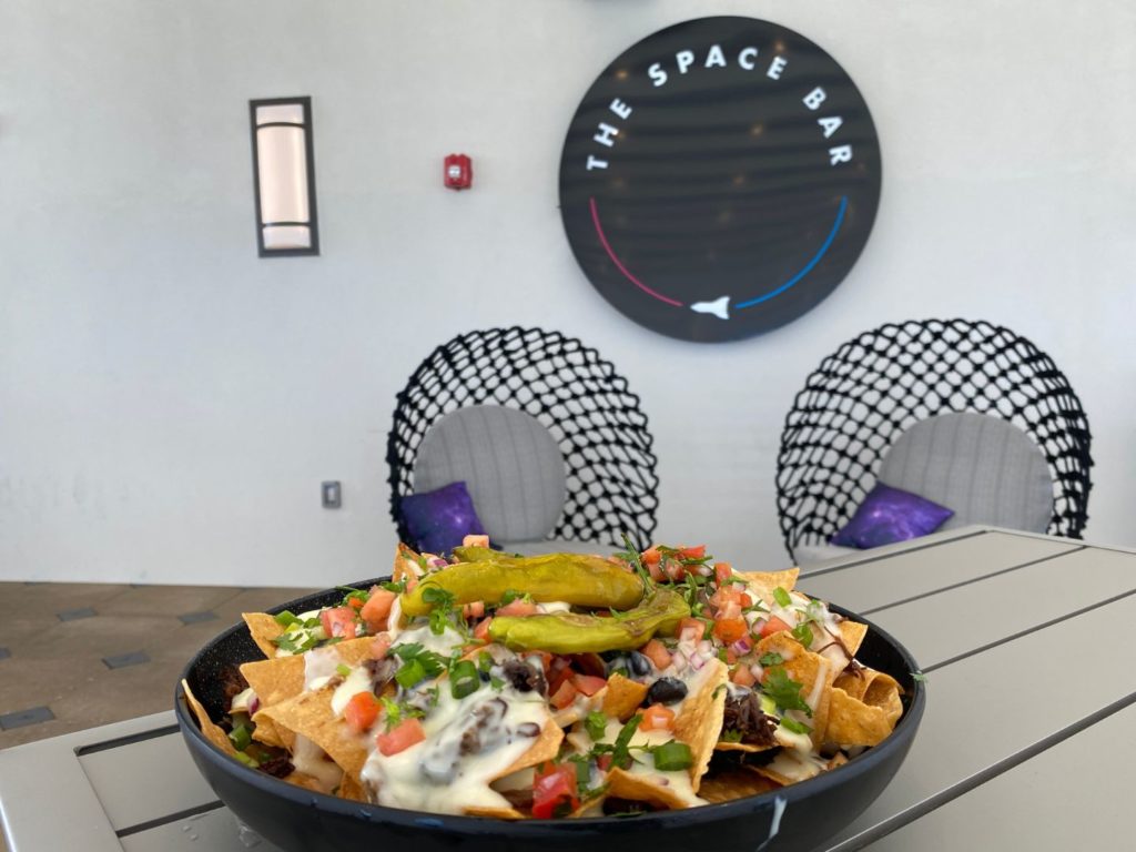 Nachos in a black bowl in front of The Space Bar sign