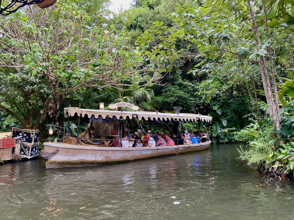 A boat ride vehicle at The Jungle Cruise Attraction at Magic Kingdom is full of guests as the boat rounds the bend in the water to return to the loading dock.