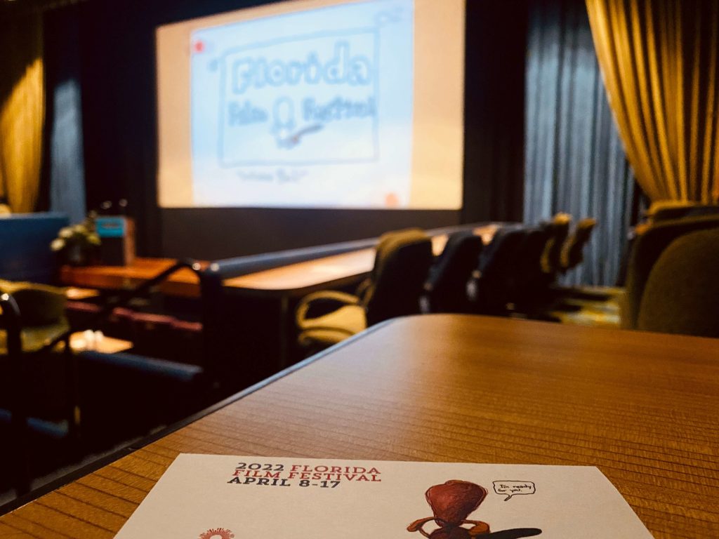 Inside the Enzian Theater with a Florida Film Festival 2022 guide placed on a table facing the movie screen