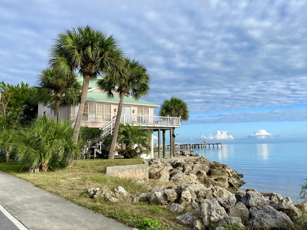 Cedar Key Florida - Corner of G Street and 2nd Street with gulf water, rocks, palm trees, and a tropical home