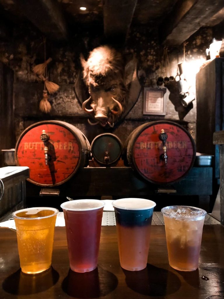 Hog's Head Pub Harry Potter Drinks - four lined up on bar in front of barrel props