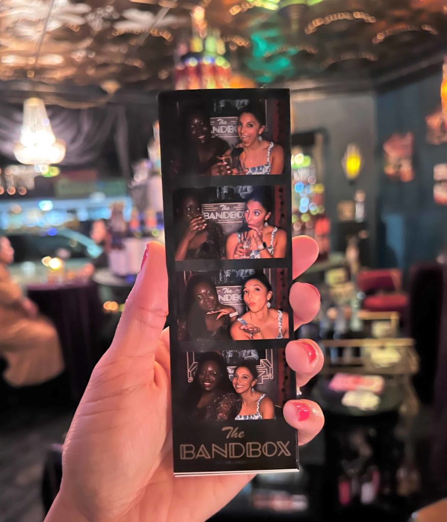 A woman with red nail polish holds a photo print out from theFree photo booth at The Bandbox Orlando 