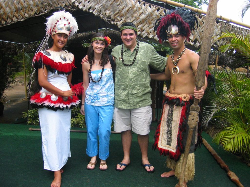 a couple poses in between two performers at An Authentic Luau in Hawaii