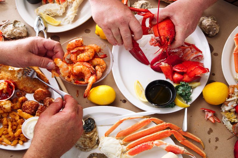 Image of two sets of hands and a lot of seafood