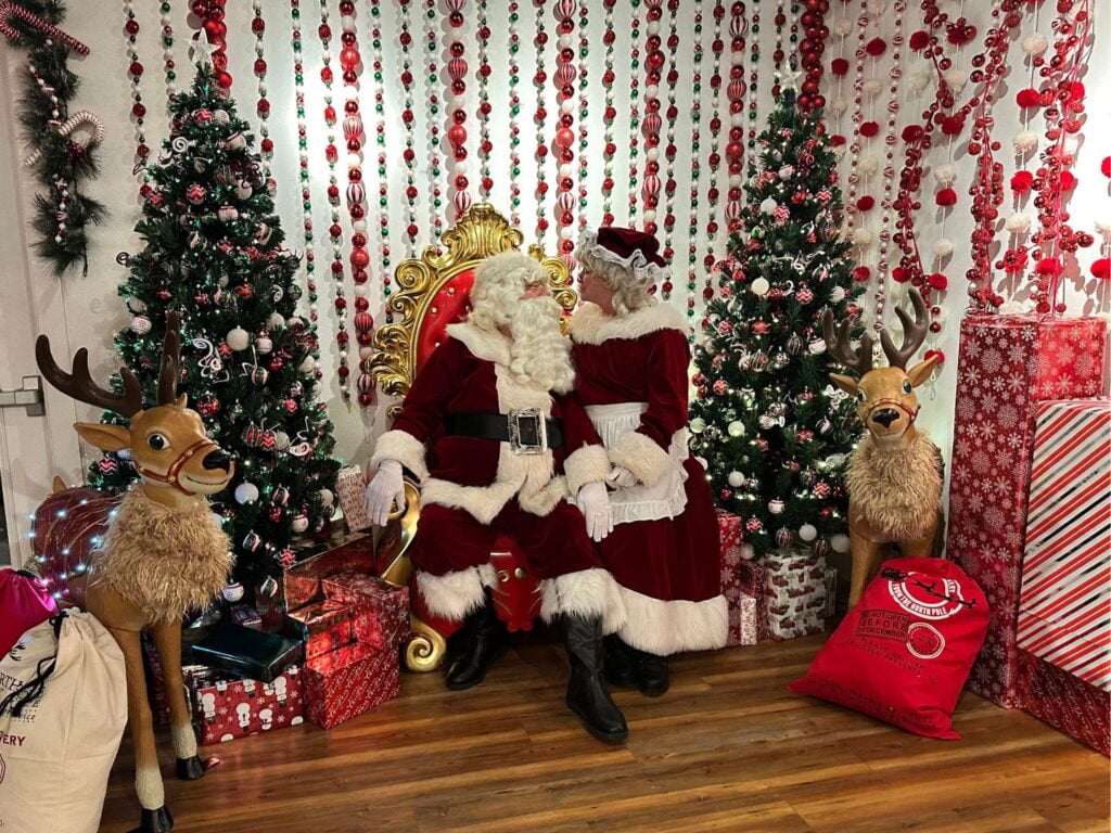 Santa and Mrs. Claus at Wekiva Island Santa's Workshop sitting on chair with festive decorations