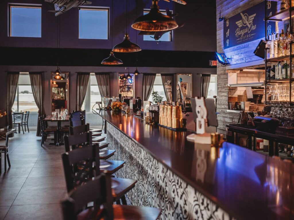 Dimly lit bar and dining room of Hanger One Bistro in St. Augustine with unoccupied chairs