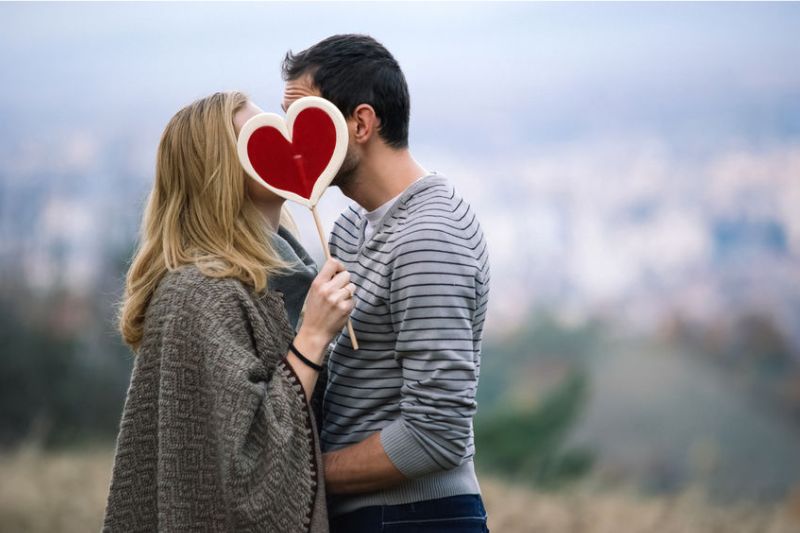 Couple kissing behind heart sign