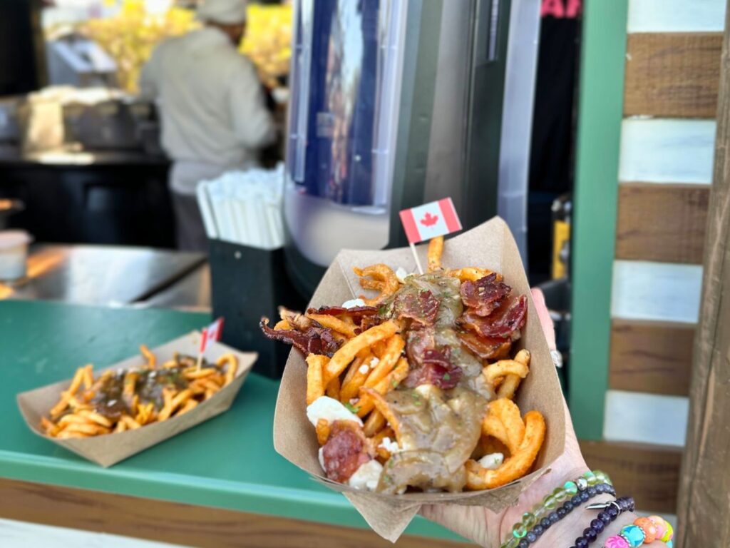 holding up the Candied Bacon Poutine at Universal Mardi Gras 2024 