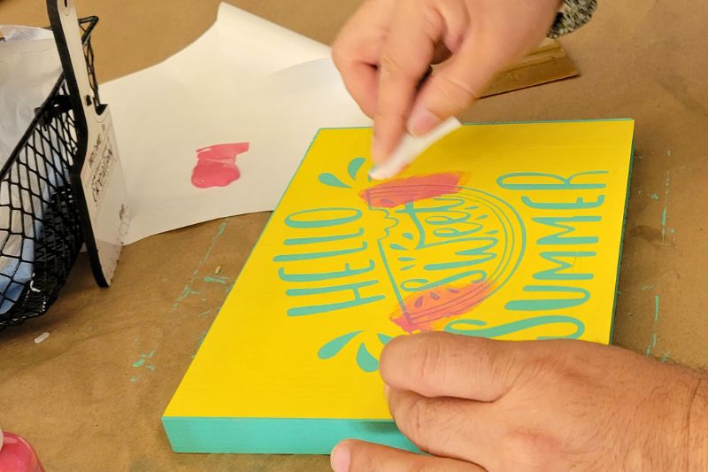 a man works on a summer themed painted sign at once upon a creation art studio in clermont florida