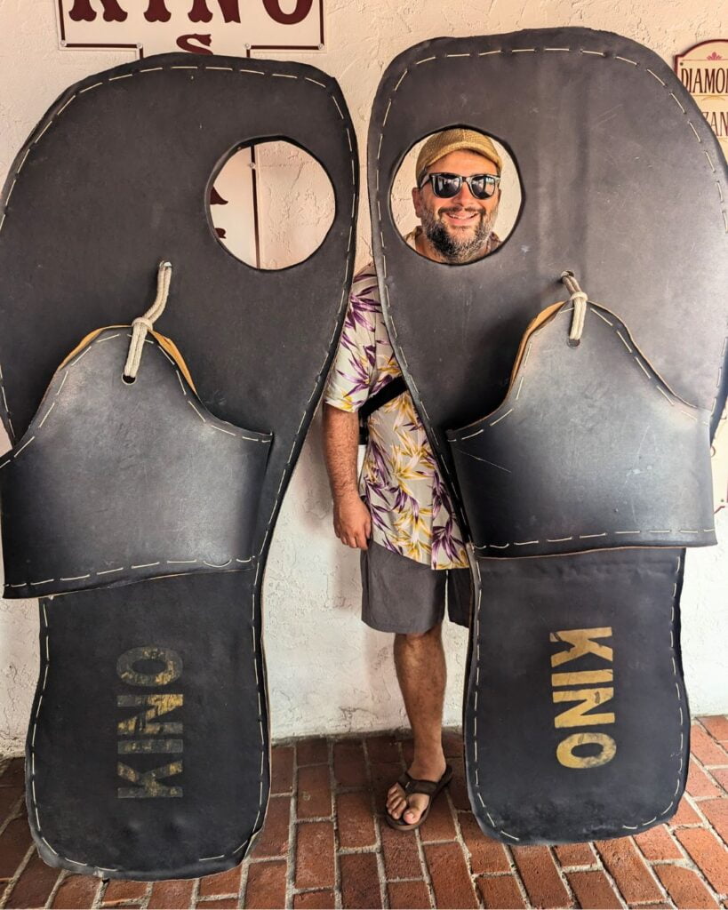 Image of a smiling man in a photo op of large flip flops at Kinos Key West