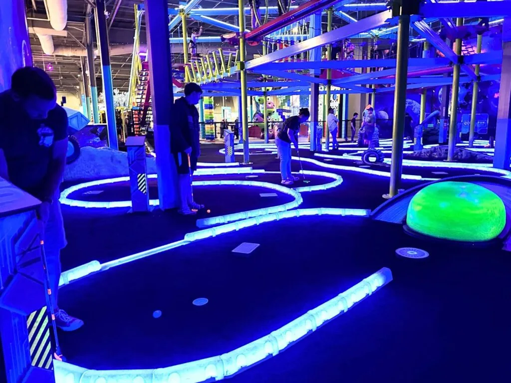 Man gets ready to put at Black Light Mini Golf at Elev8 Orlando in Sanford - image by Dani Meyering