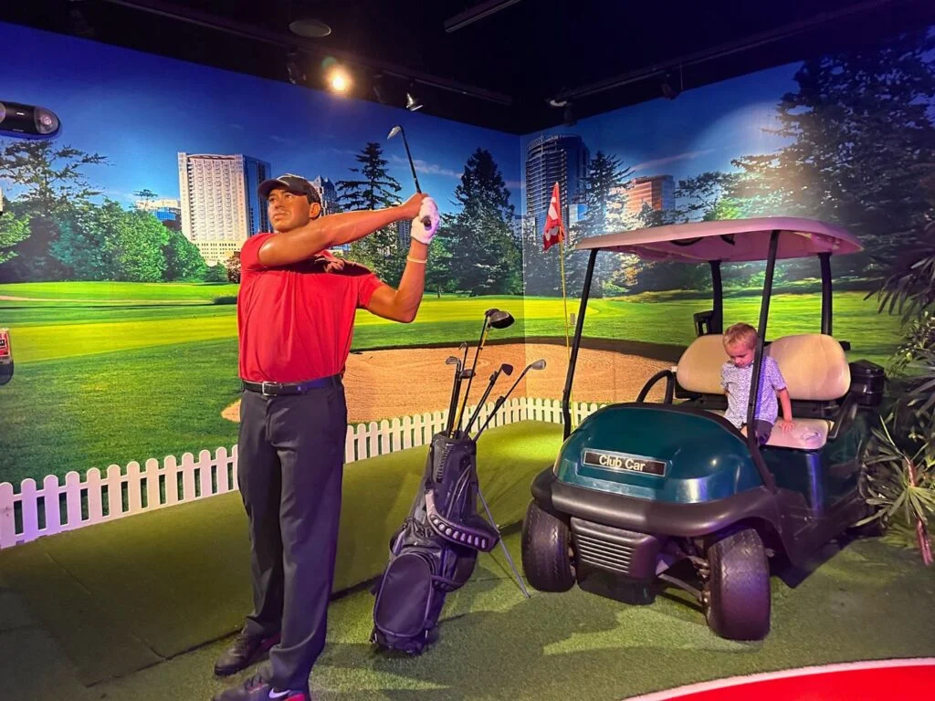 a young boy poses for photo with Tiger Woods Figure at Madame Tussauds orlando