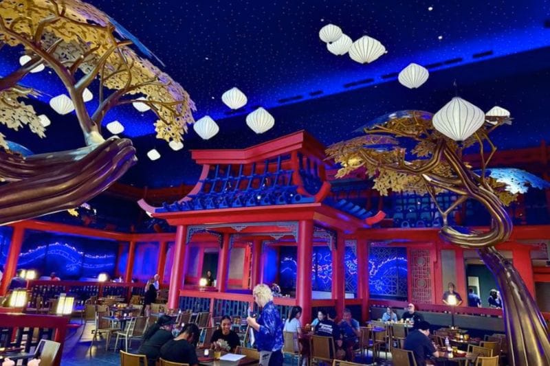 waitress at table Asian decor and nighttime inspired dining room at Blue Dragon Epic Universe - image by Jodi Caballero