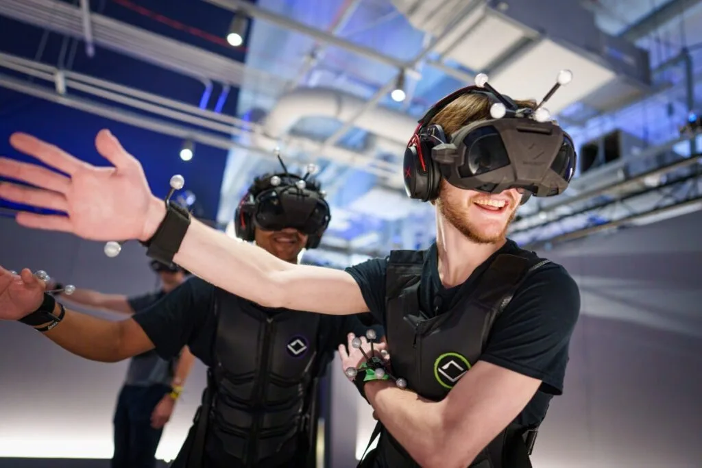 three men use VR equipment headset wrist bands and vest