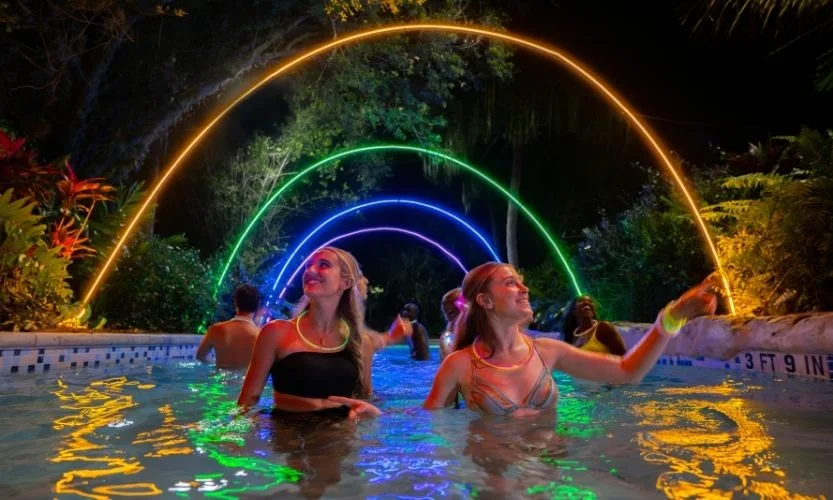 Two girls in the water under glowing lights at Aquatica Orlando for AquaGlow