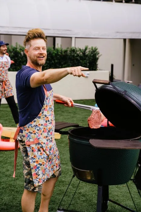 Award-winning chef, Richard Blais grilling a big steak wearing an apron